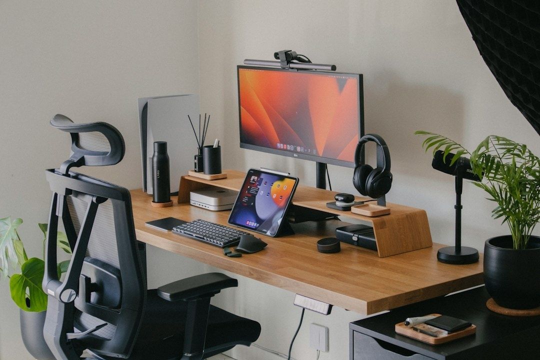 Minimalistiskt hemmakontor med skärm, surfplatta och växter